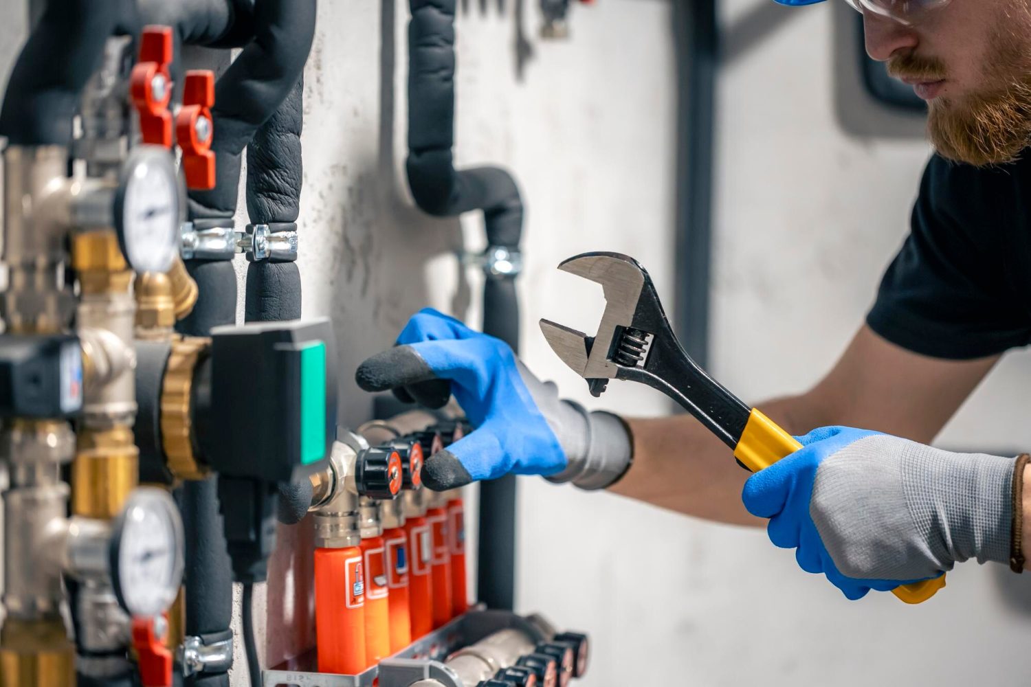 man-installs-heating-system-house-checks-pipes-with-wrench_169016-52877